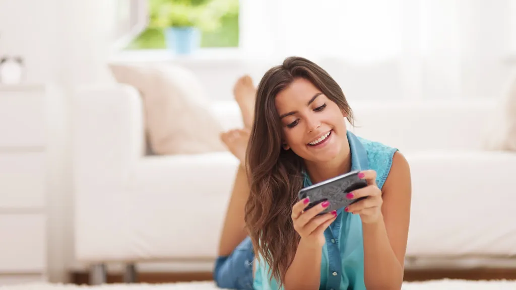 Person relaxing on a sofa while checking a smartphone