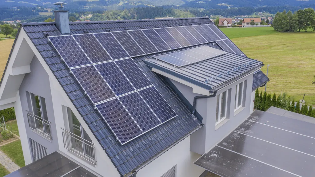 Aerial view of a detached house with a full array of black solar modules on its roof