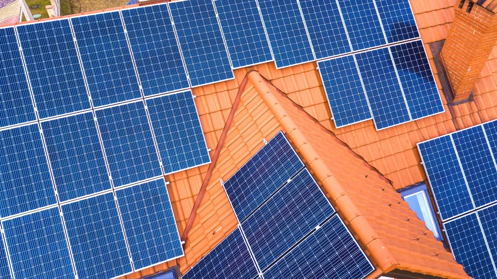 Top-down view of solar modules on a terracotta tiled roof, showing cell layout and frames